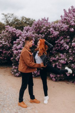 Bir çift genç adam ve güzel kadın parkta poz veriyor, gülümsüyor, birlikte eğleniyorlar.