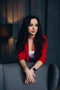 Kırmızı ceketli güzel, genç esmer kadın lambanın yanında poz veriyor. 