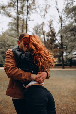 Parkta birbirine aşık genç bir çift sarılıyor. 