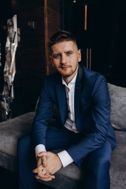 Klasik takım elbiseli genç, zarif iş adamı otel odasının içinde poz veriyor..