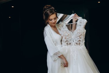 Güzel mutlu genç gelinin portresi zarif bir gelinlik tutuyor.          