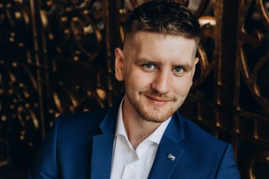 Klasik takım elbiseli genç, zarif iş adamı otel odasının içinde poz veriyor..