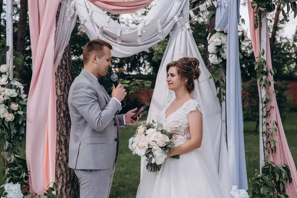 Güzel, mutlu, genç gelin ve damat açık havada evleniyor.