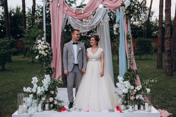 Güzel, mutlu, genç gelin ve damat açık havada evleniyor.