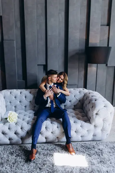 Stüdyoda gri koltukta poz veren genç ve güzel bir çift.