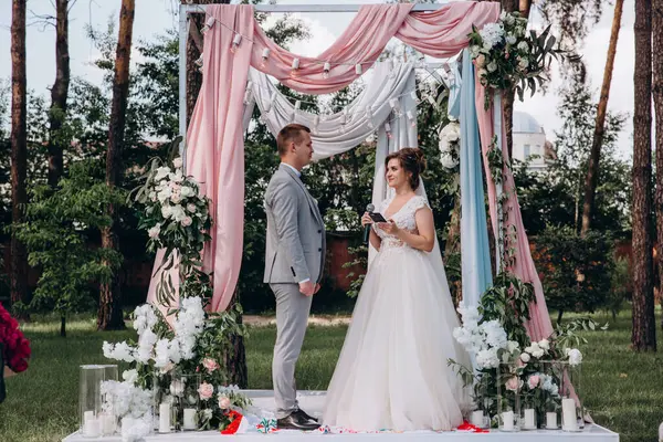 Güzel, mutlu, genç gelin ve damat açık havada evleniyor.