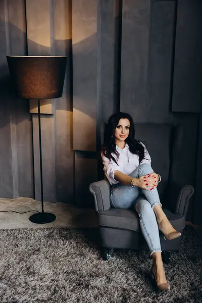 Stüdyoda poz veren kot pantolonlu ve gömlekli esmer kadın. 