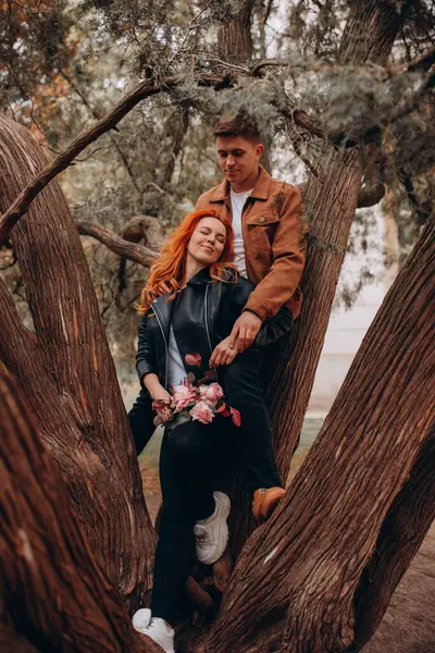 Genç ve güzel bir çift çiçek açan çalılara karşı poz veriyor. 