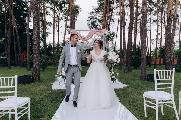 Güzel, mutlu, genç gelin ve damat açık havada evleniyor.