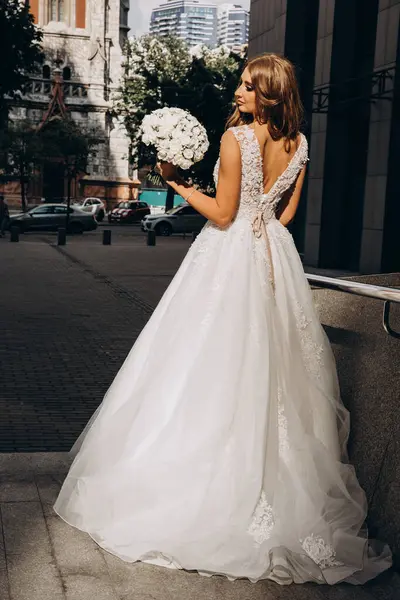 Beyaz gelinlikli güzel gelin şehirde poz veriyor.             