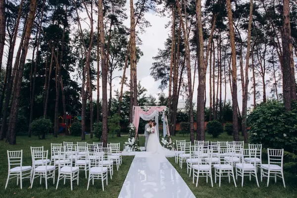 Düğün kemerinin yanında poz veren mutlu gelin ve damat parktaki düğün töreninde            