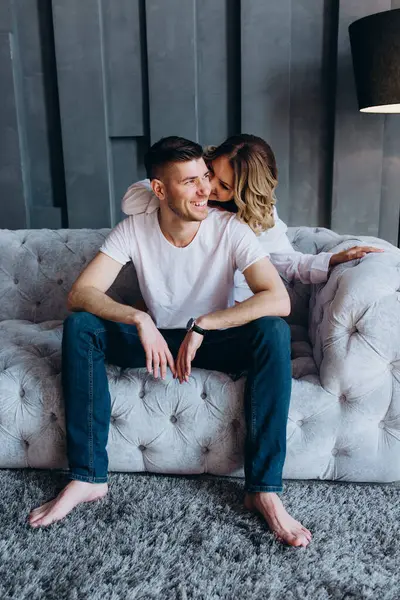 Genç çift kanepede oturuyor ve odada sarılıyorlar.