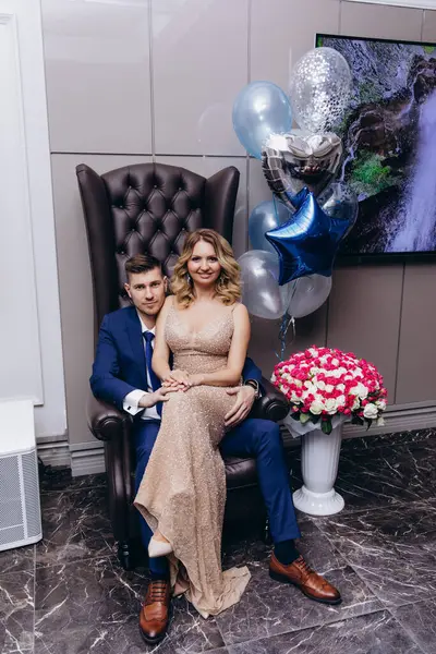 Birlikte oturan ve kameraya gülümseyen zarif genç çift.