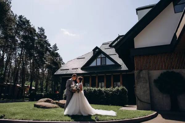 Mutlu gelin ve damat evin yanında poz veriyor.