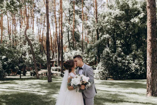 Mutlu genç gelin ve damat parkta öpüşme              