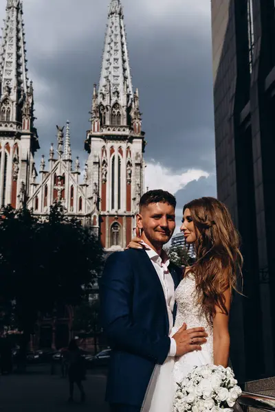 Güzel, genç, mutlu gelin ve damat düğün gününde şehirde         