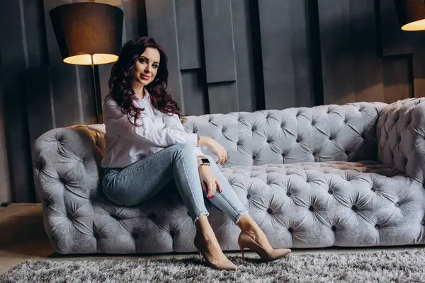 Stüdyoda gri koltukta poz veren güzel esmer kadın.