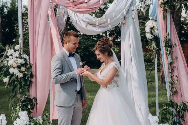 Düğün kemerinin yanında poz veren mutlu gelin ve damat parktaki düğün töreninde            