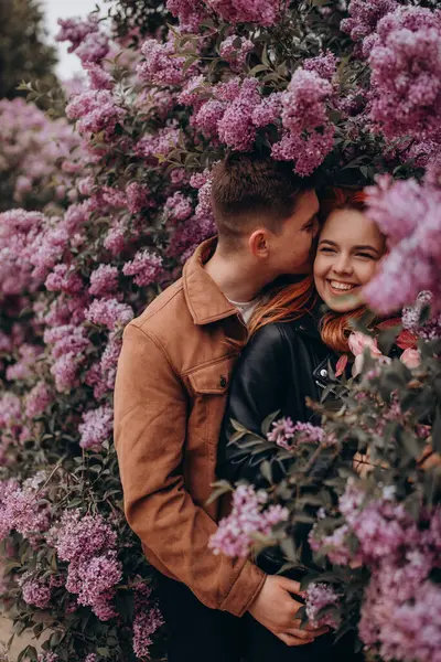 Genç çift parkta sarılıp öpüşüyor. 