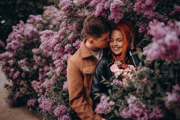 Genç çift parkta sarılıp öpüşüyor. 