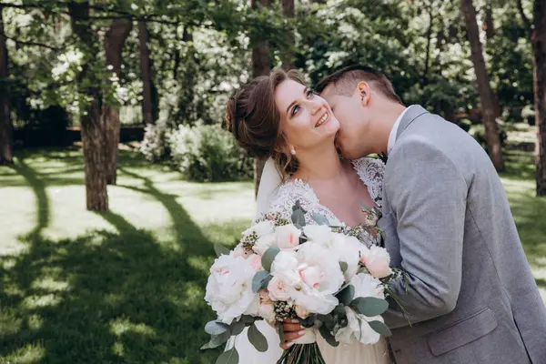 Mutlu genç gelin ve damat parkta öpüşme              