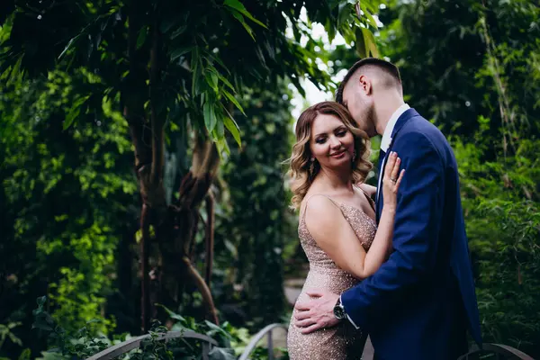 Mutlu gelin ve damat botanik bahçesinde köprüde kucaklaşıyor. 