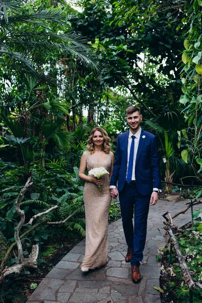 Mutlu gelin ve damat botanik bahçesinde yürüyor 