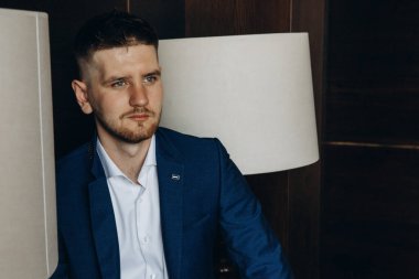 Klasik mavi takım elbiseli genç, zarif iş adamı tavan arasında poz veriyor..