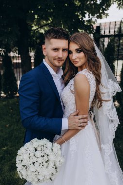 Güzel mutlu gelin ve damat düğün günü parkta poz veriyor.        