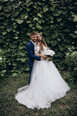 Güzel mutlu gelin ve damat düğün günü parkta poz veriyor.        