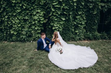 Güzel mutlu gelin ve damat düğün günü parkta poz veriyor.        