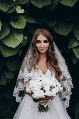 Yeşil parkta düğün buketi tutan güzel gelinin portresi.        