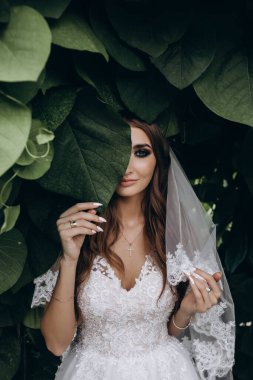 Gelinlik ve peçeyle bahçede poz veren çekici bir gelin.     