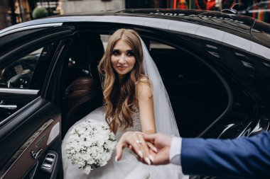 Güzel gelin ve damat arabanın yanında poz veriyorlar.