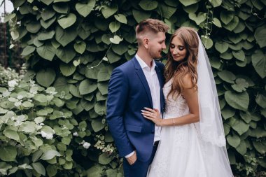 Güzel mutlu gelin ve damat düğün günü parkta poz veriyor.        