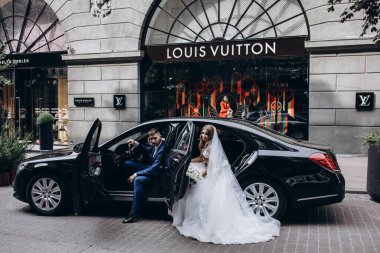 Mutlu gelin ve damat şehirde düğün gününde arabada poz veriyor..