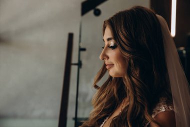 Duvağı ve düğün saç stili olan güzel gelinin yan görüntüsü