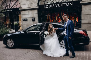 Mutlu gelin ve damat şehirde düğün gününde arabada poz veriyor..