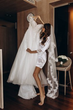 Güzel mutlu genç gelinin portresi zarif bir gelinlik tutuyor.          