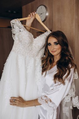 Güzel mutlu genç gelinin portresi zarif bir gelinlik tutuyor.          