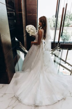 Beyaz elbiseli çekici bir gelin elinde bir buket düğün çiçeği tutuyor.                 