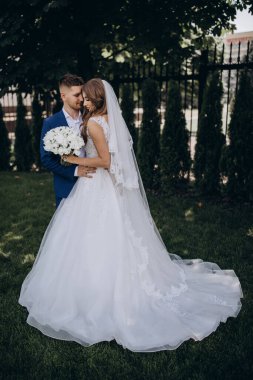 Güzel mutlu gelin ve damat düğün günü parkta poz veriyor.        