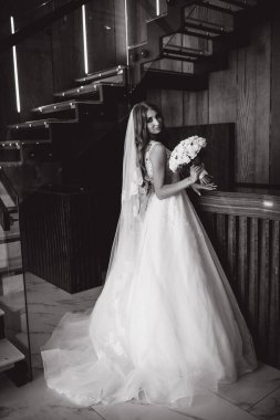 Gelinlik içinde güzel bir buket çiçek taşıyan muhteşem genç gelinin portresi.              