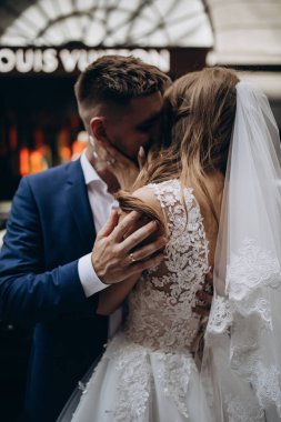 Güzel genç gelin ve damat düğün günü şehirde sarılıyor. 