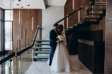 Genç gelin ve damat odada öpüşüyor.