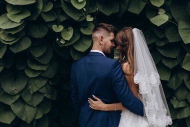 Güzel mutlu gelin ve damat düğün günü parkta poz veriyor.        