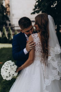 Güzel mutlu gelin ve damat düğün günü parkta poz veriyor.        