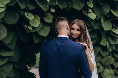 Güzel mutlu gelin ve damat düğün günü parkta poz veriyor.        