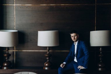 Klasik mavi takım elbiseli genç, zarif iş adamı tavan arasında poz veriyor..