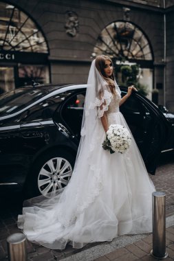 Bir buket çiçekli güzel gelin lüks bir arabayla geliyor.         